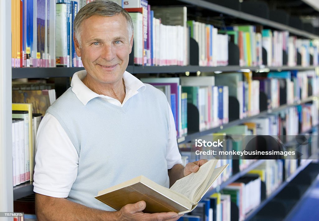 Uomo anziano, leggendo in una biblioteca - Foto stock royalty-free di Terza età