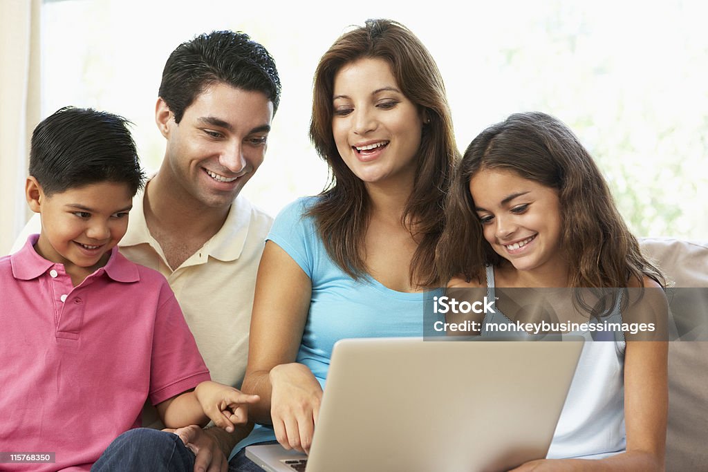 Famiglia, seduta sul divano a casa con il portatile - Foto stock royalty-free di Famiglia