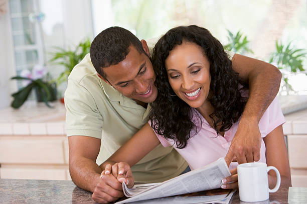 istock Couple in kitchen reading newspaper with coffee smiling 115768388