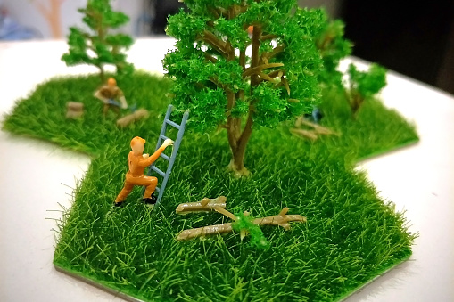 concept figure of worker using ladder to cutting big tree branch