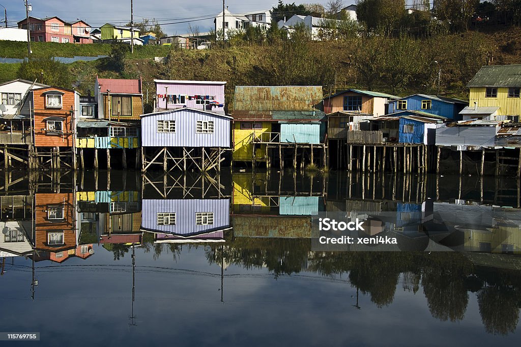 Palafito houses above the water in Castro, Chiloe, Chile Palafitos Houses are distinctive examples of Chilote architecture.  The large houses are located on the shores of the Gamboa River and the Lemuy Canal.  They are supported by thick pieces of wood embedded in the ocean floor and covered in tile roofs.  At low tide, it is possible to see where the support structure anchors into the floor of the ocean; at high tide, the houses seem to float. Architecture Stock Photo