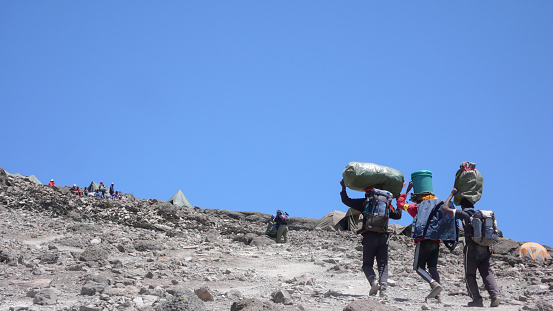 Mount Kilimanjaro / Tanzania: 5 January 2016: porters carry equipment and material to Barafu Camp on Mount Kiliimanjaro during a climbing expedition