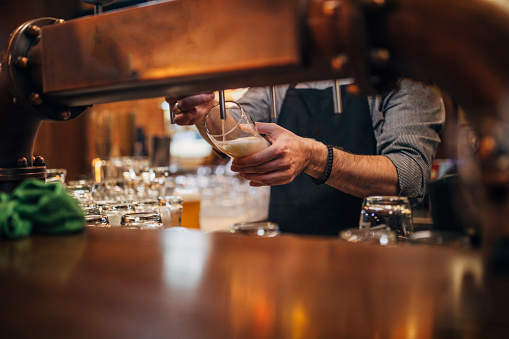 Close up of bartender pouring draft light beer in glass