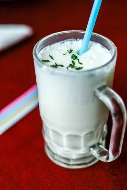Butter Milk served in a drinking glass with a drinking straw with garnishing