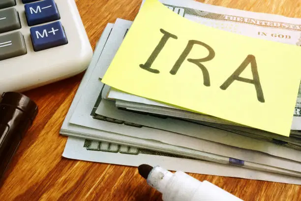 Photo of IRA individual retirement account. Stack of money and calculator.