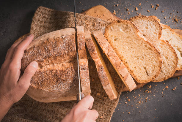 istock Fresh loaf of bread and hand dark background. 1157708768