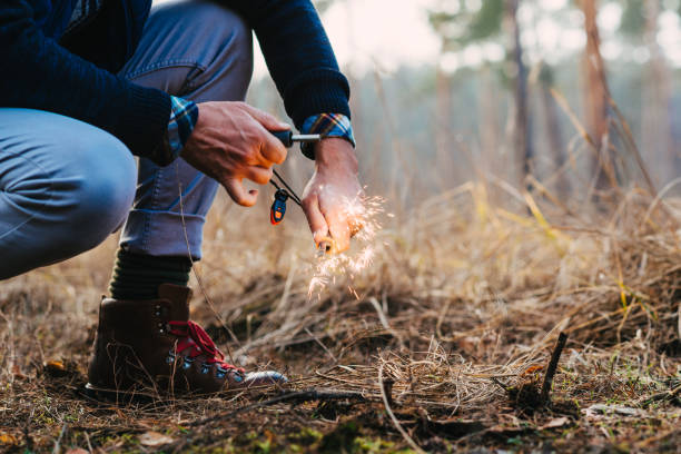 A man makes a fire with a flint A man makes a fire with a flint survival tools stock pictures, royalty-free photos & images