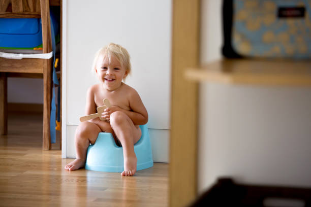 Little toddler boy, sitting on potty, playing with wooden toy Little toddler boy, sitting on potty, playing with wooden toy at home toddler hitting stock pictures, royalty-free photos & images