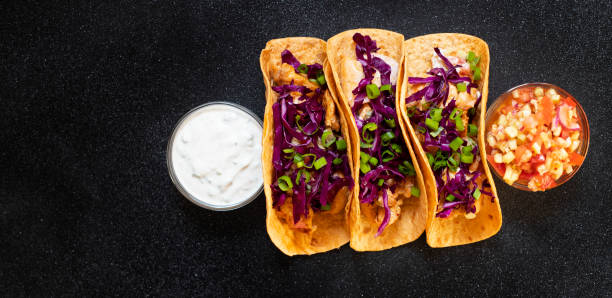 traditionelle mexikanische tacos mit huhn, gegrilltem gemüse, zwiebeln und lila kohl, serviert mit weißer und roter sauce. ansicht von oben. dunkle hintergrund. kopierraum - grilled chicken chicken corn salsa stock-fotos und bilder