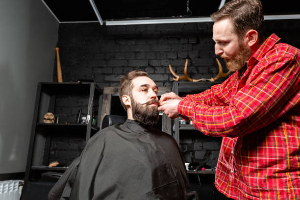istock Barber is making the beard shape. Beard cutting, face care. Work in barber shop. 1157720645