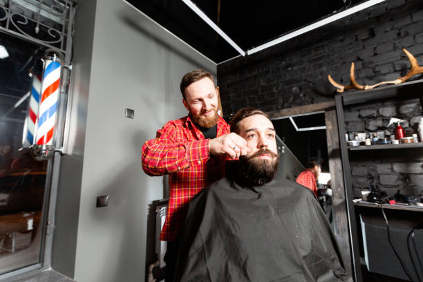 istock Barber is making the beard shape. Beard cutting, face care. Work in barber shop. 1157720659