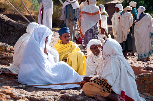 Lalibela, Ethiopia - 4 January, 2018: Group of Christian African Women in traditional white clothes sit near ancient rock-hewn Church of Saint George (Bete Giyorgis)