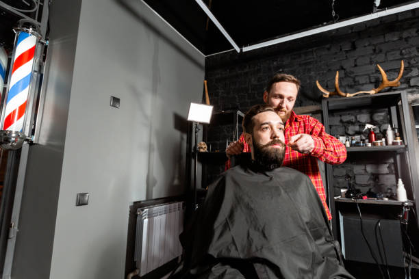 istock Barber is making the beard shape. Beard cutting, face care. Work in barber shop. 1157720705