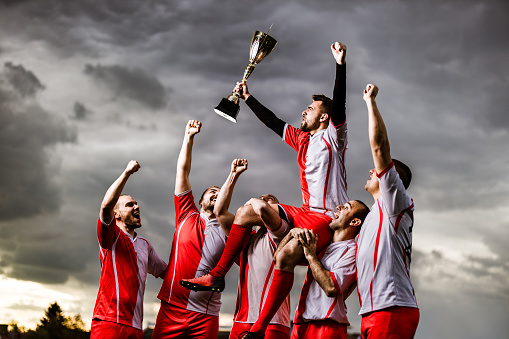 Rugby, team and winning with trophy, champion and men at stadium with success, celebration and achievement. Male people outdoor, exercise and competition, sports game and cheers with mockup space