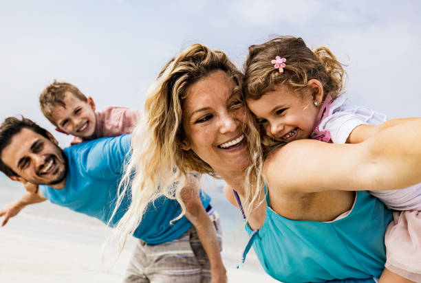 istock Playful family having fun while piggybacking on the beach. 1157724642