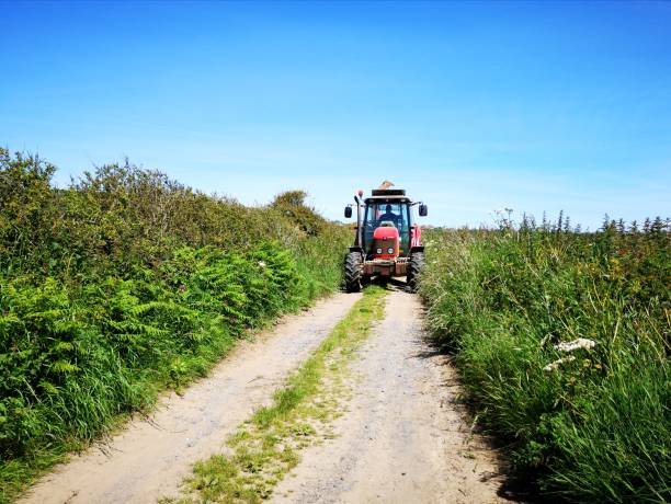 tracteur rouge dans une voie de campagne avec des haies élevées. - welsh culture wales field hedge photos et images de collection