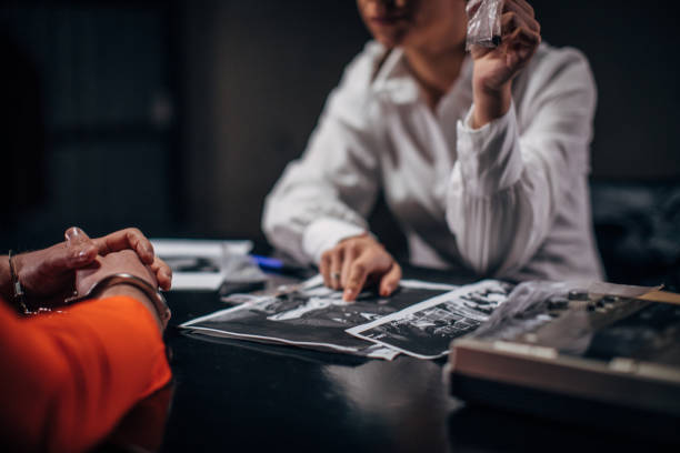 Prisoner and female detective Prisoner in orange jumpsuit with handcuffs and female detective sitting in the investigation room interrogation woman stock pictures, royalty-free photos & images