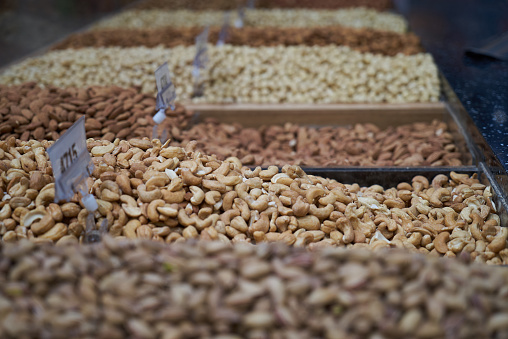 Variety of nuts on market counter, close-up. Mix of fresh nuts with price tag, selective focus