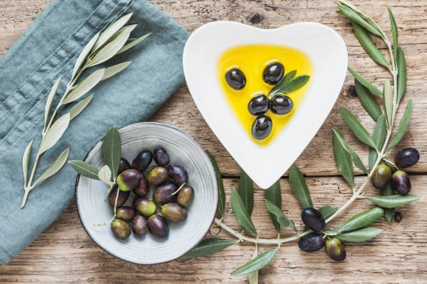istock Olive oil and olives on rustic wooden background. 1157728692