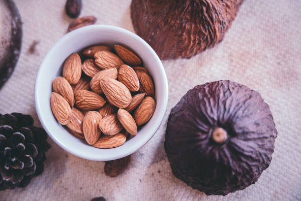 Top view almonds in a white cup on a wooden table with a cocoa effect on the side.