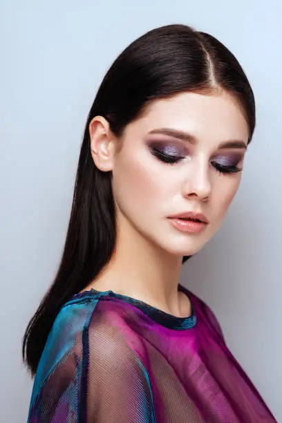 Beautiful sexy girl with professional evening makeup, perfect shining skin, dark hair. Trendy colorful smoky eyes.