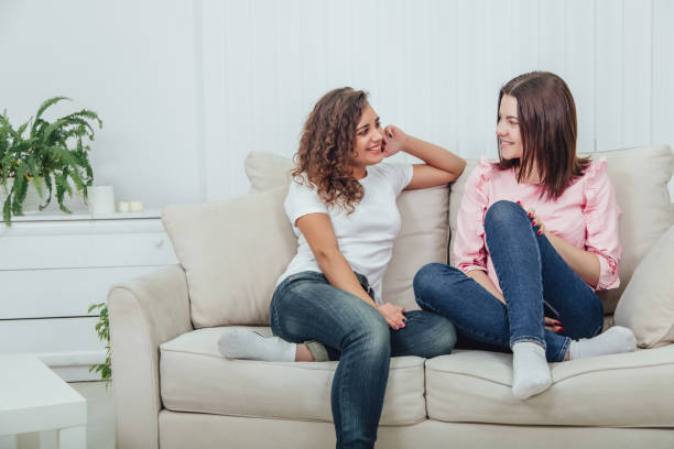 istock Two attractive girlfriends sitting on the sofa, talking excitedly, smiling. 1157732495