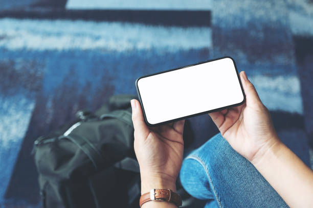istock a woman's hands holding and using black mobile phone with blank screen while sitting in the airport 1157733511