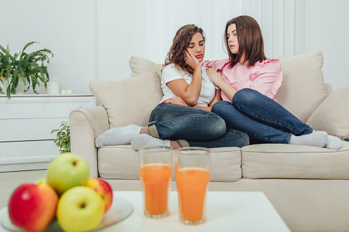 True friend will always help you. Concept of friendship and support. Apple and juice on the blurred forefront. Full-length shot of two lovely girls.