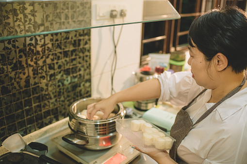 an asian chinese female preparing food for her son before going to school in the morning at kitchen