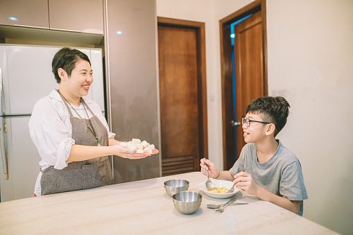 an asian chinese female mother serving steamed mantou bun bread to her sun in the morning for breakfast before he goes to school