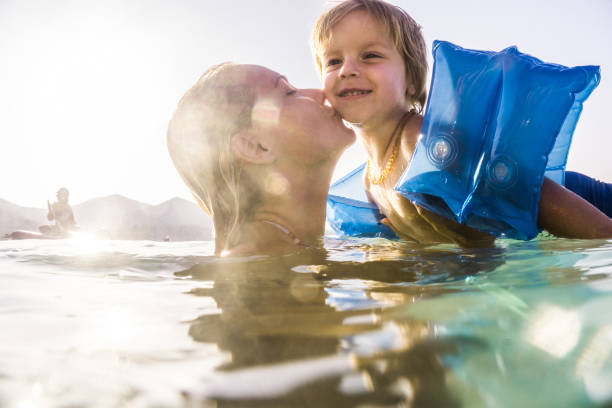 Affectionate mother kissing her small son in the sea.