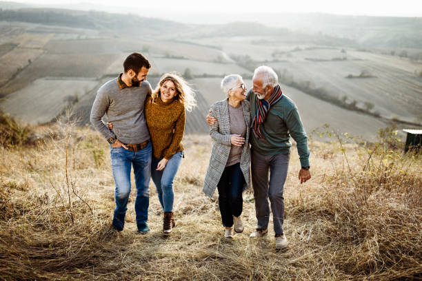 istock Happy couples talking while walking embraced in autumn day on the field. 1157735371