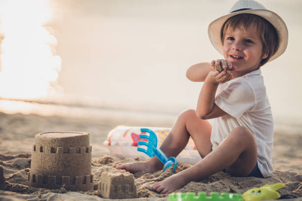 istock Cute small boy playing with sand at the beach. 1157735477
