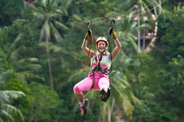 Happy woman having fun during canopy tour in the forest. Young cheerful woman rappelling from a zip line during canopy tour in nature. canopy tour photos stock pictures, royalty-free photos & images