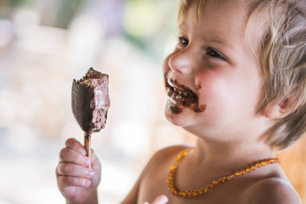 Baby girl smeared her mouth with sticky sweet ice cream in the summer.