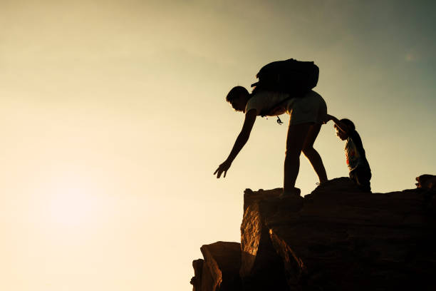 istock Family hiking to summit at sunset. Help concept 1157736344