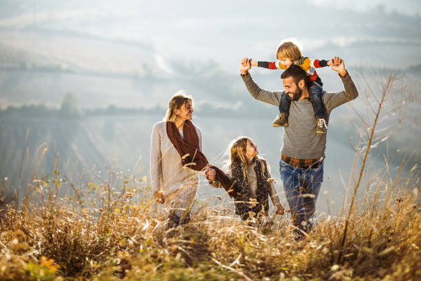 istock Carefree parents enjoying while walking with their kids on a field. 1157739519