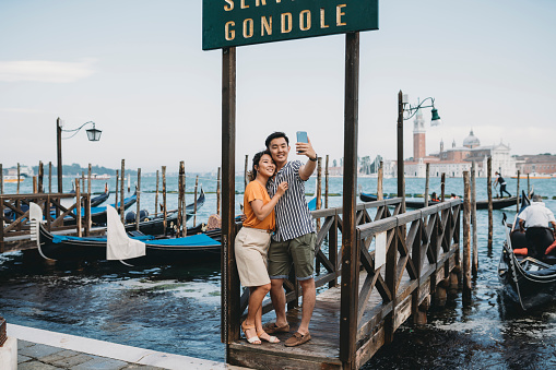 Young adult asian couple taking a selfie in Venice, Italy