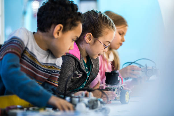 istock Group of small kids working on robots on robotics class. 1157743712