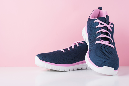 Pair of female sport shoes on pink background, close up