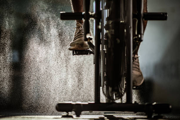 atleta masculino irreconocible haciendo ejercicio en bicicleta estática en un gimnasio. - bicicleta estática fotografías e imágenes de stock