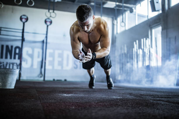 muscular build athlete clapping while exercising push-ups in a gym. - exercising men push ups muscular build imagens e fotografias de stock