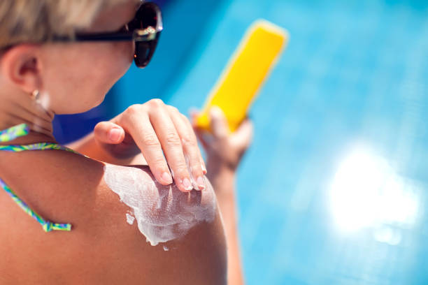 女人在她的皮膚上塗上防曬霜。人、暑假、度假和醫療保健理念 - 防曬油 個照片及圖片檔