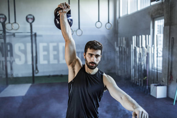 istock Young athletic man exercising with kettle bell in a gym. 1157747700