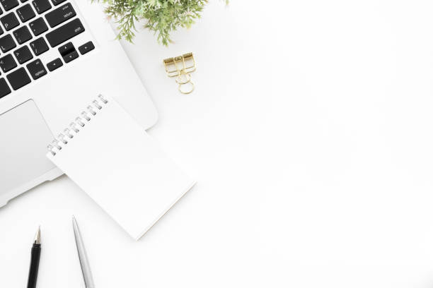 istock White office desk table with laptop computer, blank notebook and pen. Top view with copy space, flat lay. 1157749750