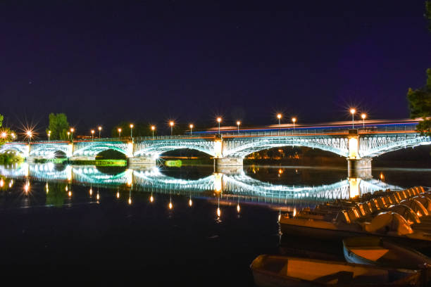 istock River crossing illuminated bridge, and bask in the foreground. 1157751593