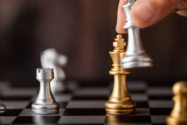istock hand holding silver king attack gold leader in game 1157752809