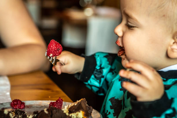 baby jongen eten dessert met een vork. - foto’s van jongen stockfoto's en -beelden