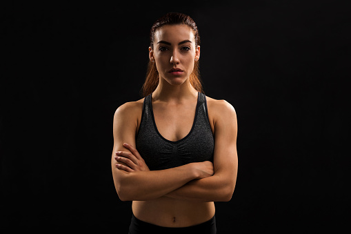 Caucasian young female athlete standing with arms crossed against plain background