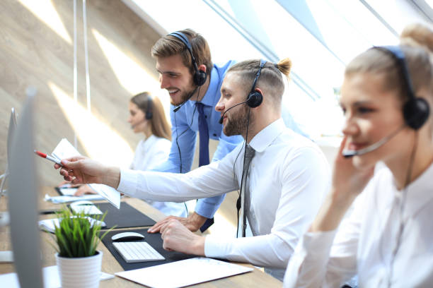 istock Phone operator working at call centre office helping hiss colleague. 1157755183